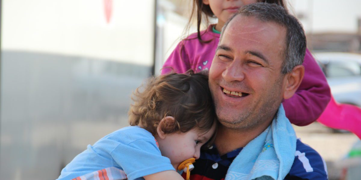 Un padre iraquí pasa el rato con sus hijos frente a su 