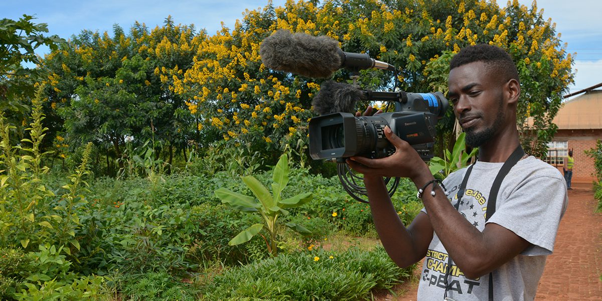 Hugo, journaliste communautaire en action avec sa caméra dans le camp de réfugiés Dzaleka (JRS)