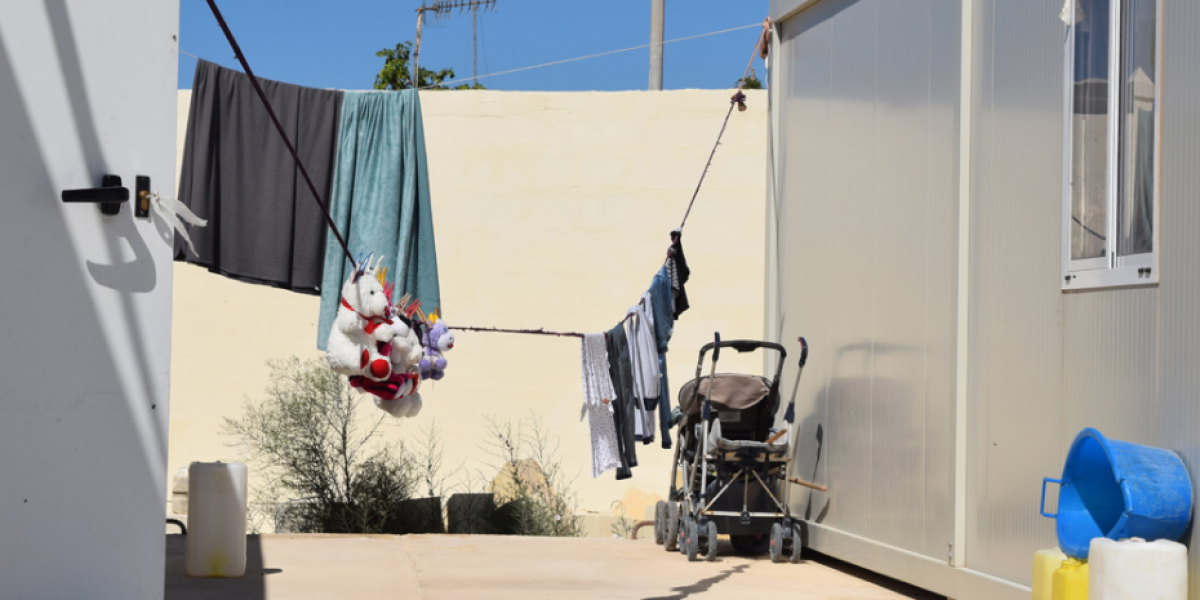 Juguetes de peluche cuelgan entre los containers reconvertidos en casas en un centro abierto en Malta.