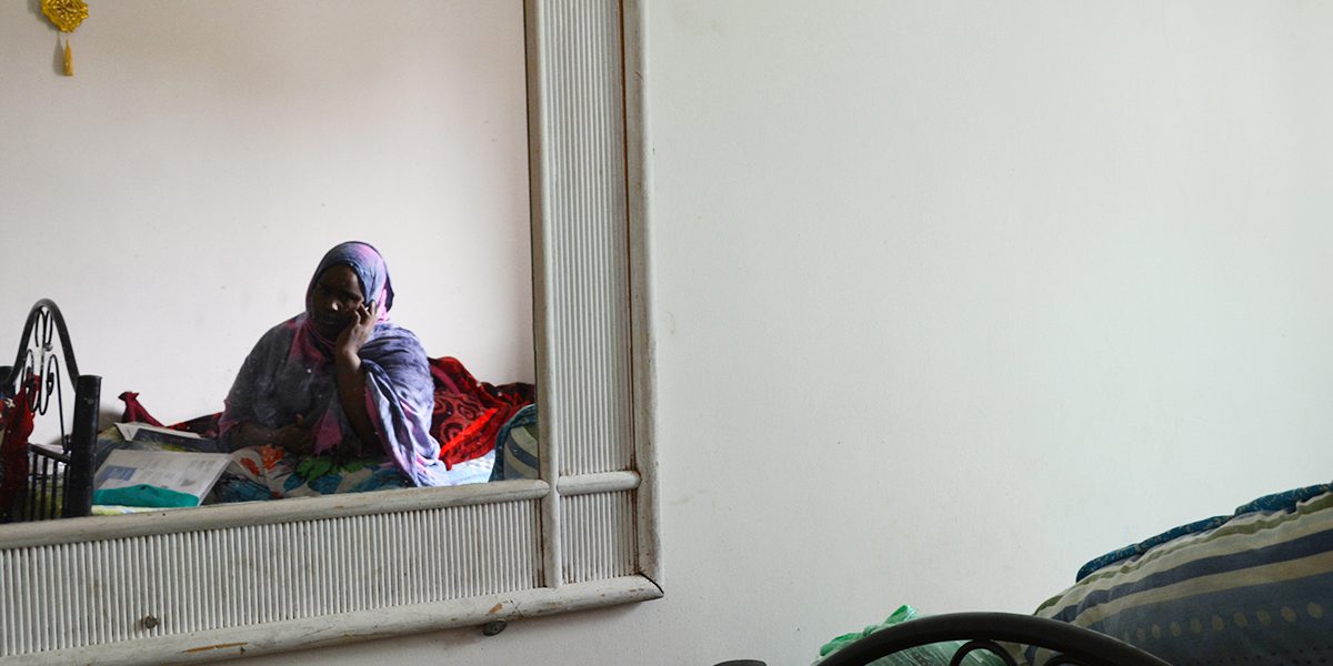 A young Somali woman on the phone in her small, one-bedroom apartment in Amman.