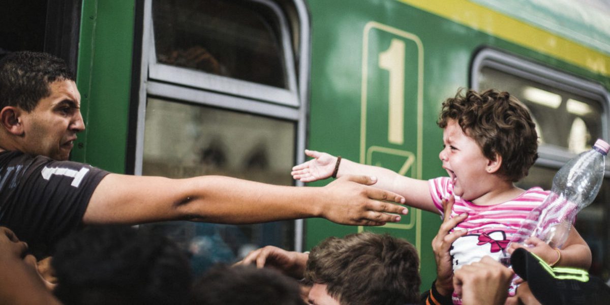 From a train, this man, between tears and rage, tries to touch his child.