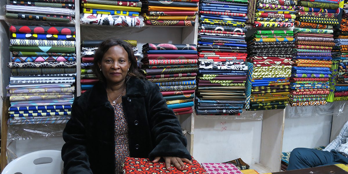 Janette se sienta en su tienda de ropa en Uganda.