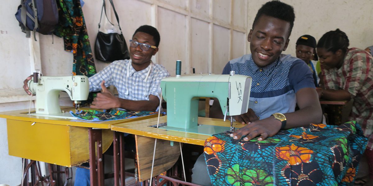 Dos estudiantes trabajan diligentemente en la clase de costura del JRS en Kampala.